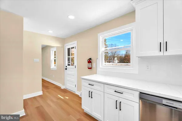 a hallway with white cabinets and wooden floor