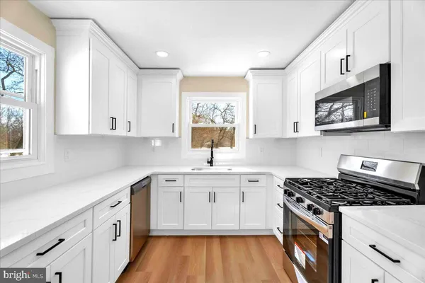 a kitchen with stainless steel appliances white cabinets stove and sink
