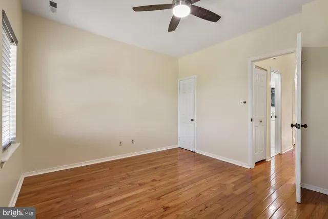 an empty room with wooden floor fan and windows