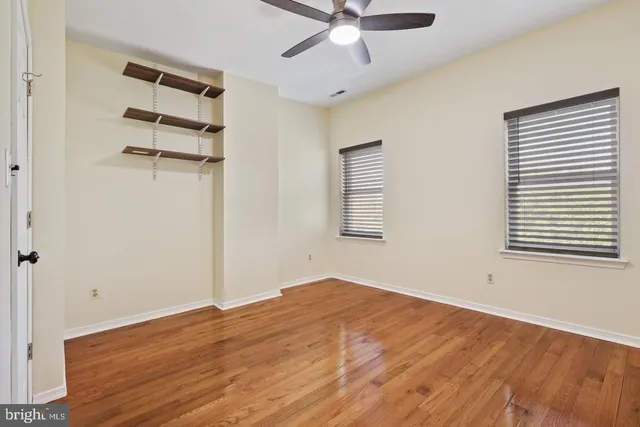 a view of empty room with wooden floor and fan