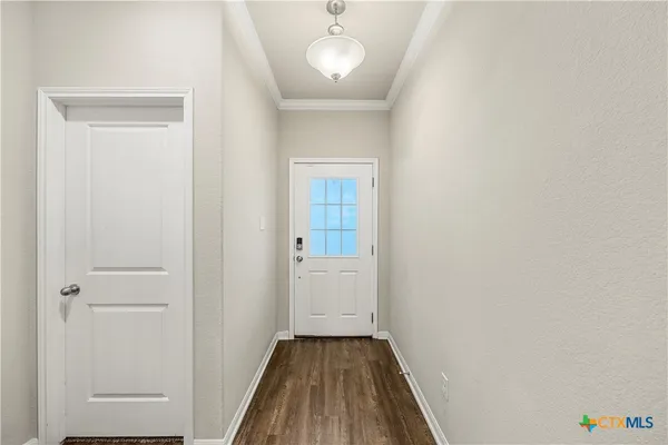 a view of a hallway with wooden floor and a chandelier