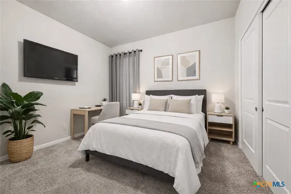 a spacious bedroom with a bed and a flat screen tv