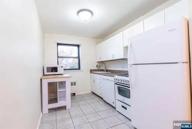 a kitchen with granite countertop white cabinets and white appliances