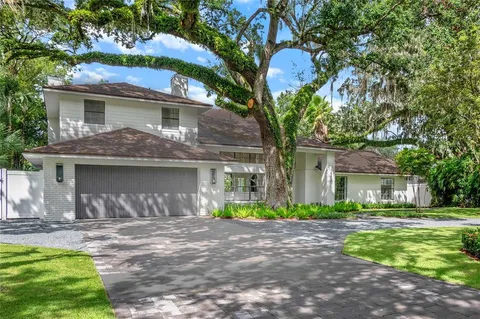 a front view of a house with a garden and tree