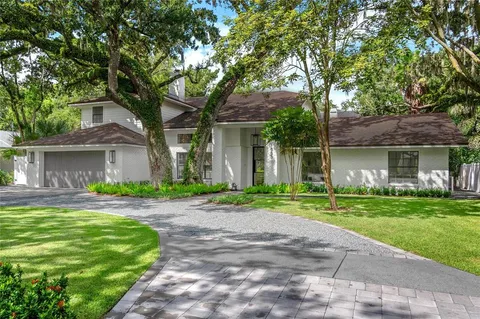 a front view of a house with a garden and trees