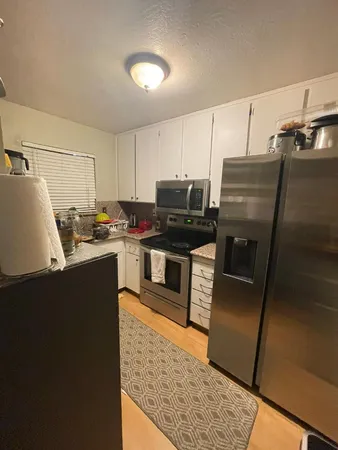 a kitchen with granite countertop a refrigerator and a stove top oven