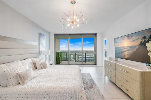 a bedroom with a large bed and a flat tv screen on dresser