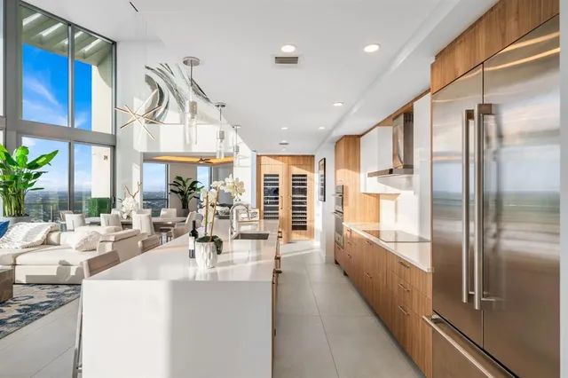 a large kitchen with kitchen island a large window cabinets a sink and stainless steel appliances
