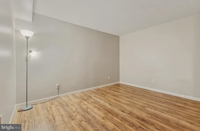 a view of an empty room with wooden floor and closet