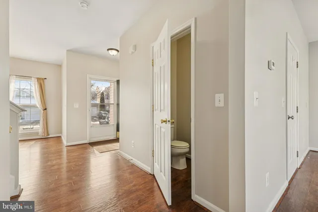 a view of an empty room and bathroom with wooden floor