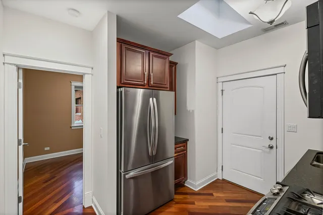 a view of a refrigerator in kitchen and an empty room