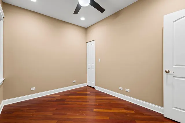 an empty room with wooden floor and ceiling fan