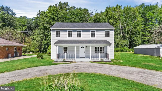 a front view of a house with a garden and trees