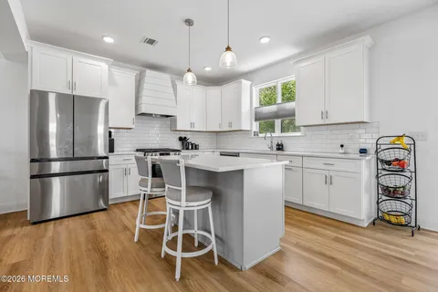 a kitchen with a refrigerator a white cabinets and wooden floor