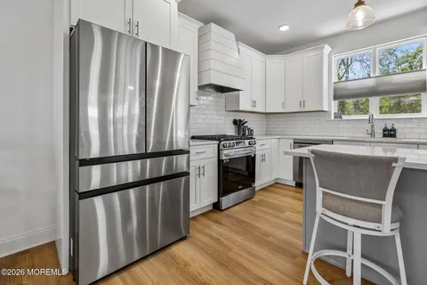 a kitchen with wooden floors stainless steel appliances and white cabinets