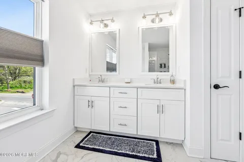 a bathroom with a double vanity sink a mirror and a window