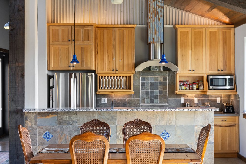 1292 Upper Turtle Creek Road Kerrville, TX 78028 - Photo 7 of 40 Kitchen featuring stainless steel appliances, backsplash, light stone counters, a breakfast bar, and wooden ceiling