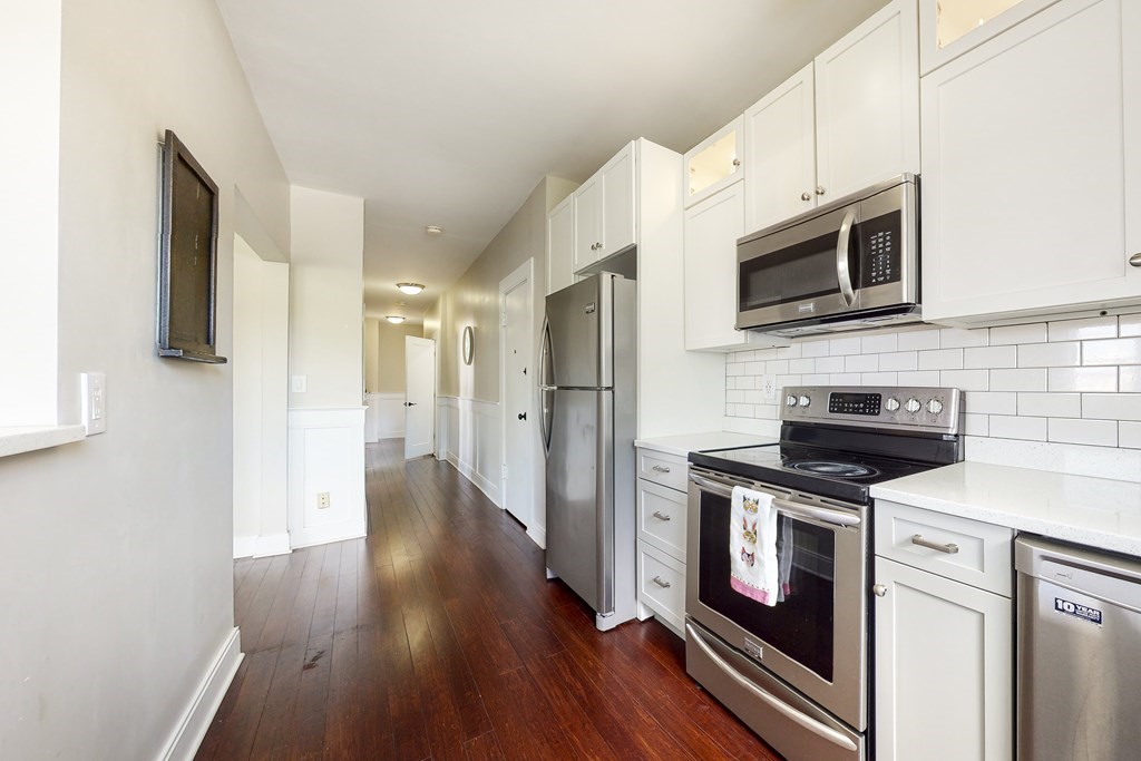 1834 Beacon Street, Unit 16 Brookline, MA 02445 - Photo 15 of 21 a kitchen with stainless steel appliances granite countertop a stove a refrigerator and a microwave