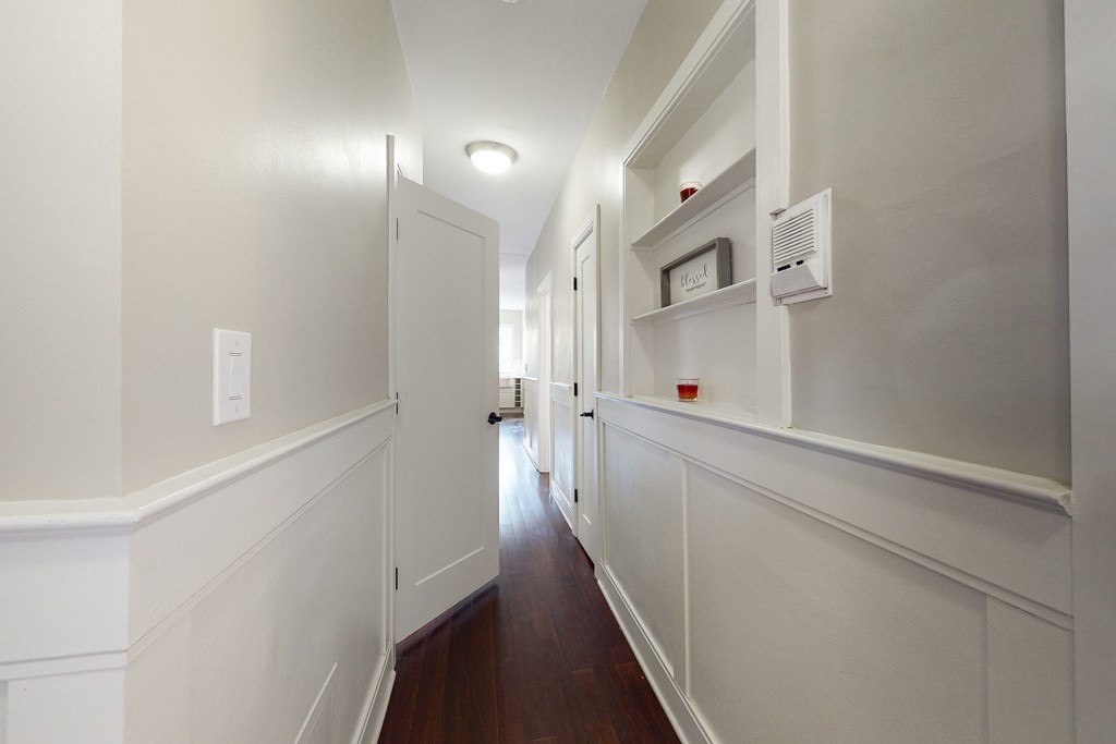 1834 Beacon Street, Unit 16 Brookline, MA 02445 - Photo 3 of 21 a hallway with white cabinets and wooden floor