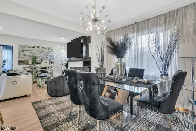 a living room with furniture a chandelier a large window and a flat screen tv
