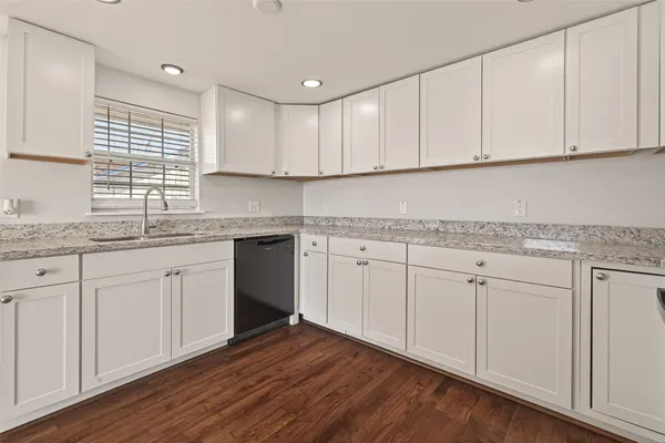 a kitchen with granite countertop white cabinets white appliances and a wide window