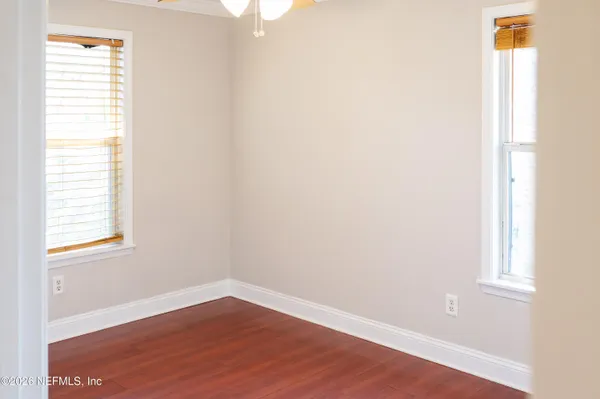 a view of an empty room with wooden floor and a window