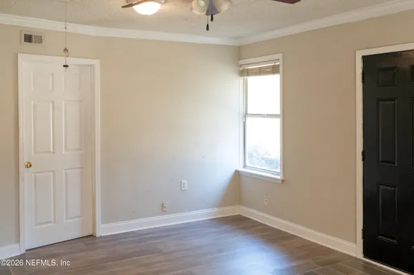 a view of an empty room with wooden floor and a window