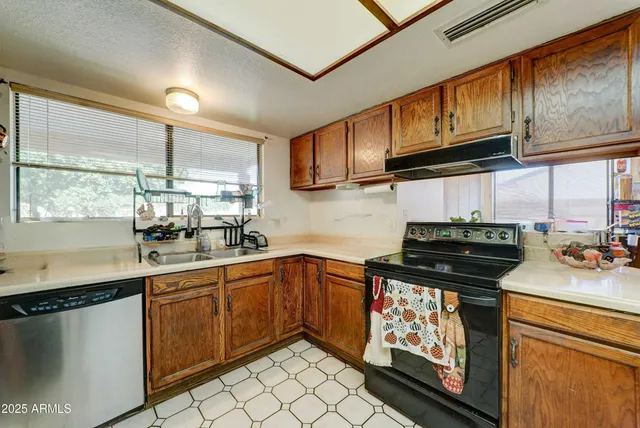 a kitchen with stainless steel appliances granite countertop a sink a stove a counter space and cabinets