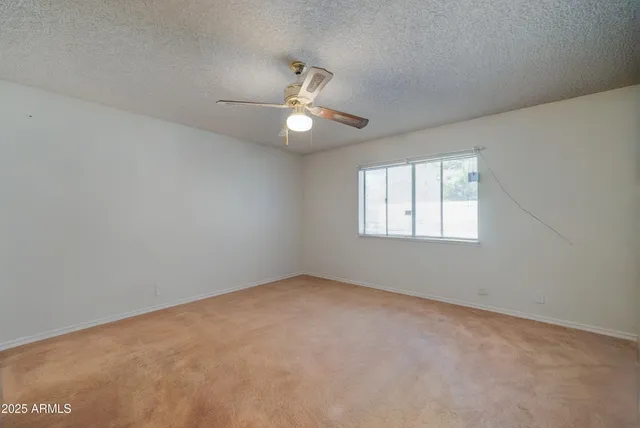 an empty room with a window and ceiling fan