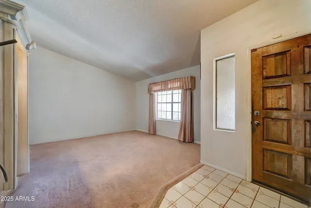 a view of an empty room with window and refrigerator
