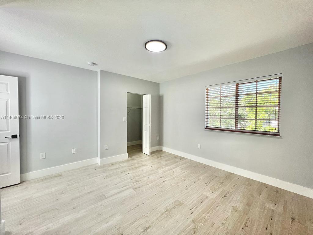 14116 Southwest 260th Street, Unit 106 Homestead, FL 33032 - Photo 10 of 24 an empty room with wooden floor and windows
