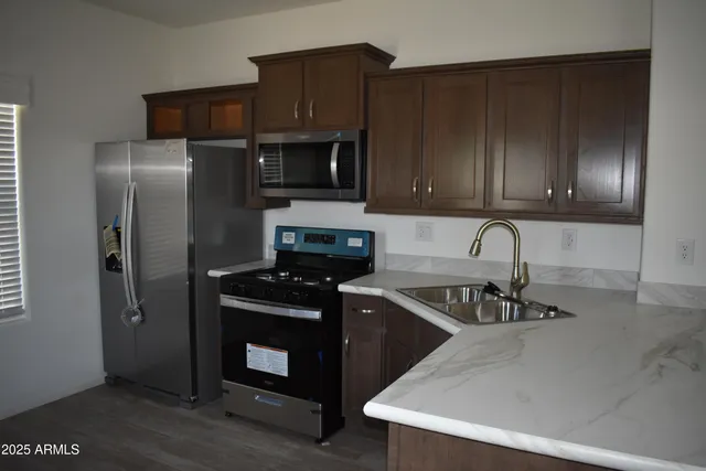 a kitchen with granite countertop a refrigerator stove and microwave