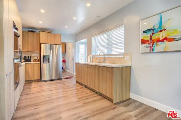 a view of a kitchen with wooden floor and stainless steel appliances