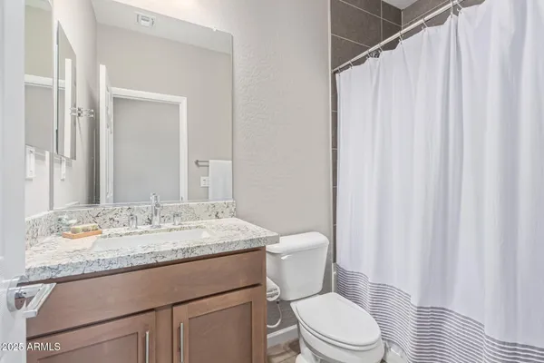 a bathroom with a granite countertop sink toilet and a mirror