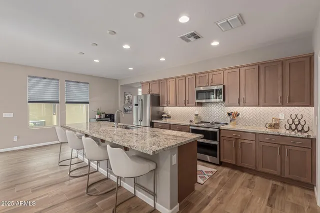 a kitchen with stainless steel appliances granite countertop a table chairs sink refrigerator and cabinets