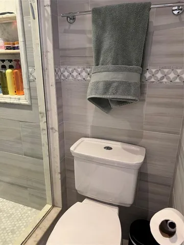 a white toilet sitting next to a shower