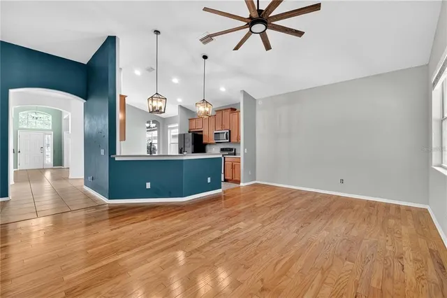 a view of empty room with wooden floor and fan