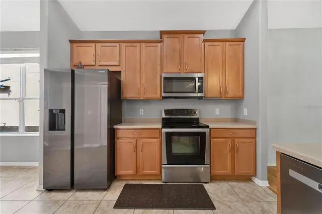 a view of a refrigerator in kitchen and an empty room in wooden floor