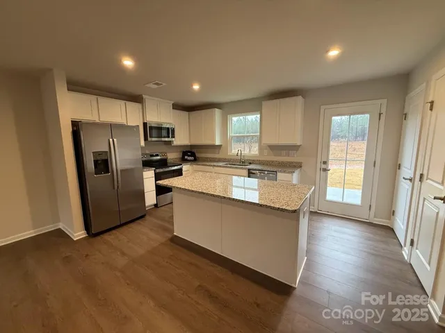 a kitchen with stainless steel appliances granite countertop a refrigerator a stove a sink and a microwave