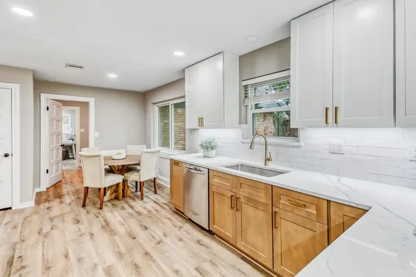 a kitchen with granite countertop sink stove and white cabinets with wooden floor