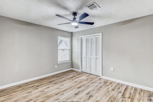 a view of empty room with wooden floor and fan