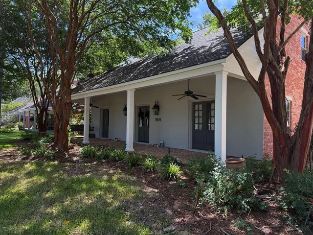a view of a house with a yard and large tree
