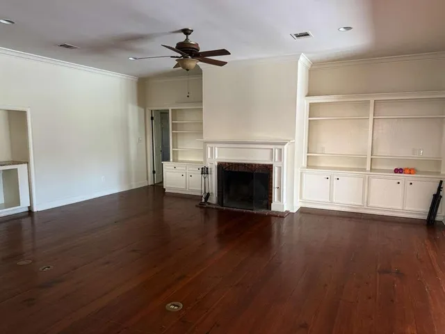 an empty room with wooden floor fireplace and windows