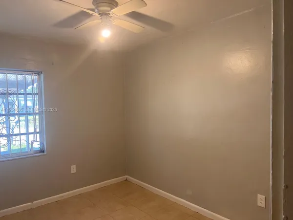 an empty room with a ceiling fan and window