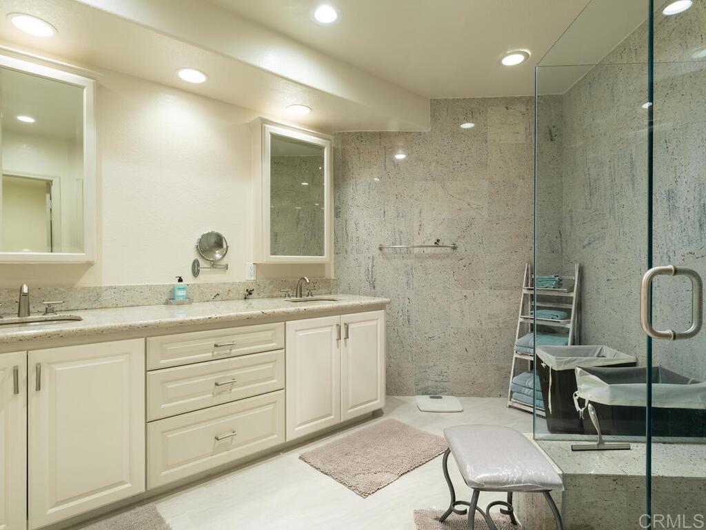 1099 1st Street, Unit 217 Coronado, CA 92118 - Photo 24 of 32 a bathroom with a granite countertop sink a toilet a mirror and shower
