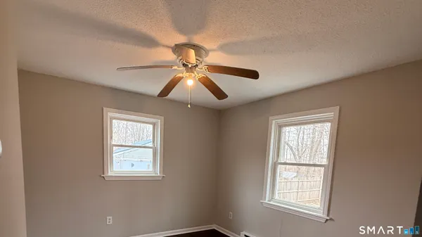 an empty room with windows and fan