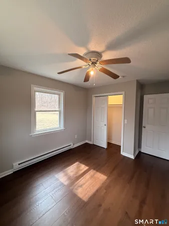 an empty room with wooden floor chandelier fan and windows