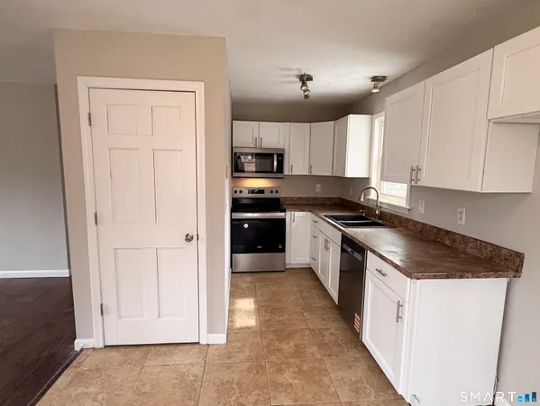 a kitchen with kitchen island white cabinets and stainless steel appliances