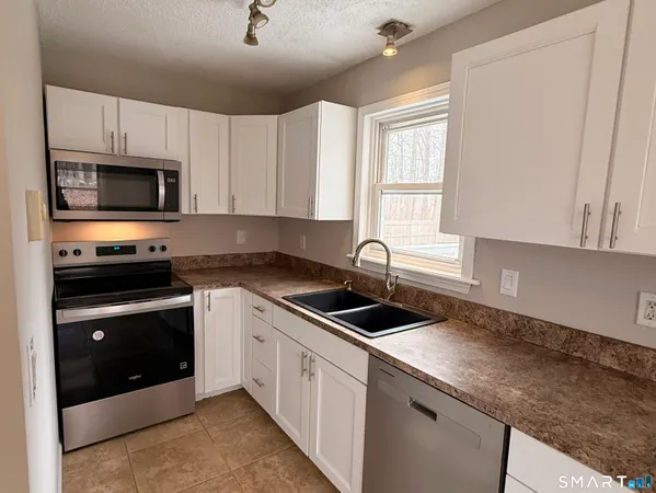 a kitchen with granite countertop a sink stainless steel appliances and cabinets