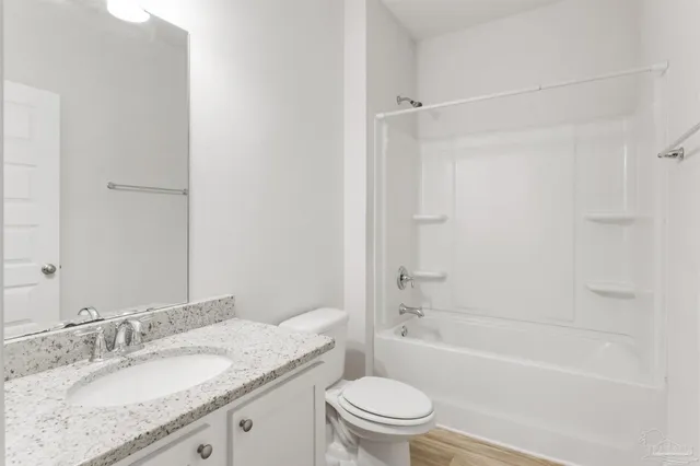 a bathroom with a granite countertop bathtub shower sink vanity mirror and toilet
